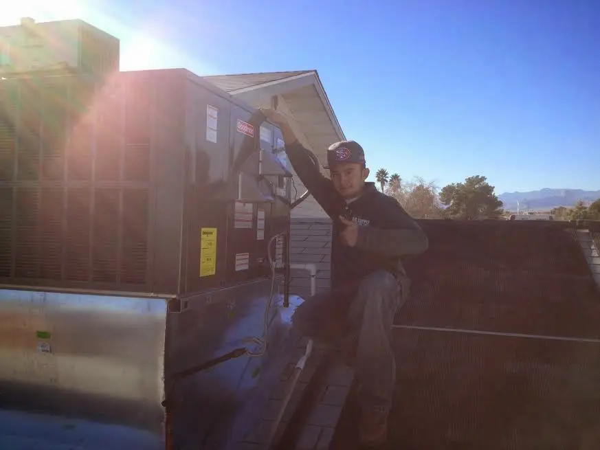 HVAC technician performing AC Tune-Up on a rooftop unit in Alamosa